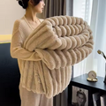  Personne tenant une couverture camel pliée, à texture duveteuse et reliefs en larges bandes