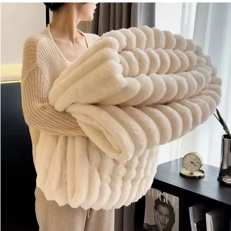  Personne tenant une couverture blanche pliée, à texture duveteuse et reliefs en larges bandes. 