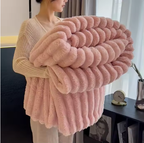  Personne tenant une couverture rose pliée, à texture duveteuse et reliefs en larges bandes